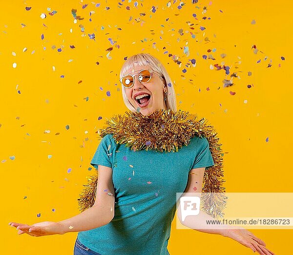 Konfetti-Party bei einer Feier  blonde kaukasische Mädchen im Studio auf gelbem Hintergrund