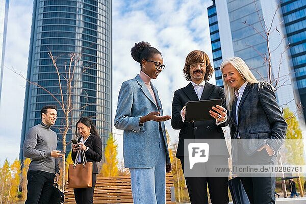 Multiethnische Geschäftskollegen oder Führungskräfte  die sich mit Technologie und gläsernen Bürogebäuden befassen