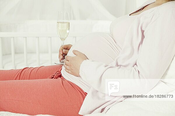 Schwangere Frau mit einem Sektglas am Babybauch