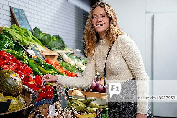 Porträt einer kaukasischen Frau  die im Lebensmittelgeschäft Gemüse und Grünzeug kauft