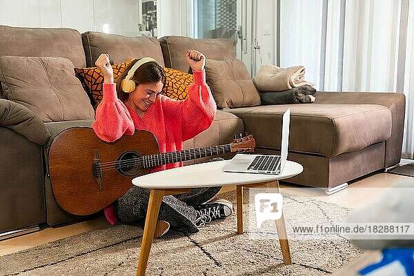Frau lernt zu Hause Gitarre spielen  sehr glücklich  weil sie das Lied gut gespielt hat