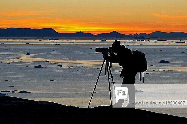 Tourist at sunset taking pictures of the Kangia Icefjord  an UNESCO-World Heritage Site at Disko-Bay  West-Greenland  Greenland  North America