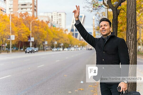 Kaukasischer Geschäftsmann mittleren Alters  der ein Taxi ruft und die Hand hebt  um zur Arbeit zu fahren  lächelnd