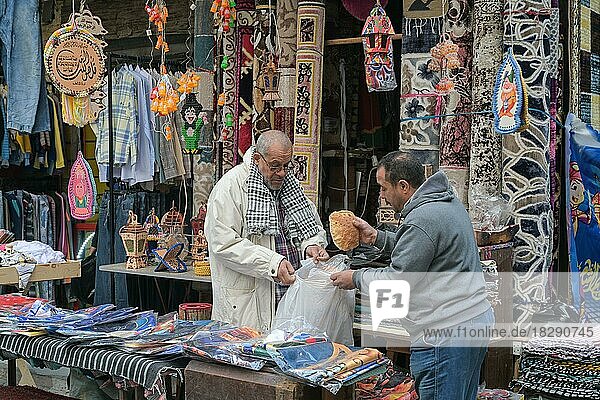 Street scene  textile shop  carpets  men  bread  Khan el-Khalili bazaar  Old City  Cairo  Egypt  Africa