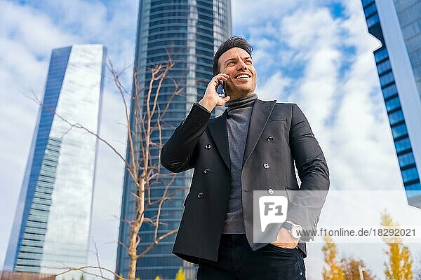 Unternehmensporträt eines Geschäftsmannes mittleren Alters  der neben einem Hochhausbüro telefoniert