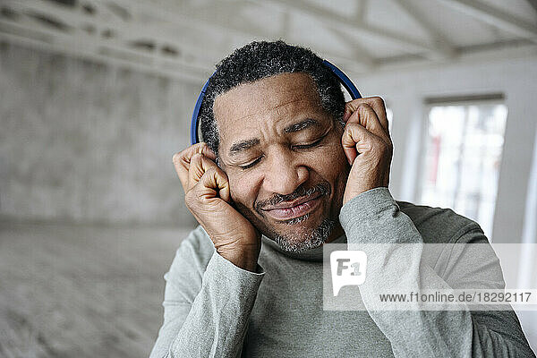Man enjoying music listening through wireless headphones at home