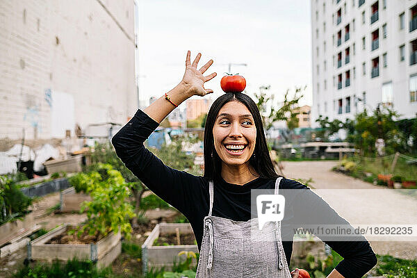 Happy woman with tomato on head standing in urban garden