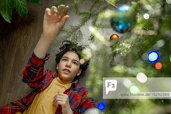Boy lying under Christmas tree at home