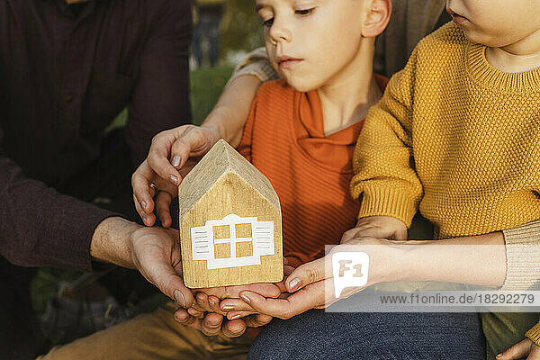 Parents with sons holding wooden toy house