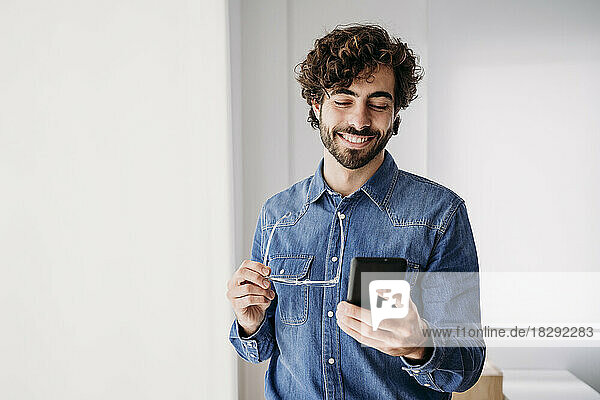 Smiling young entrepreneur using mobile phone in office