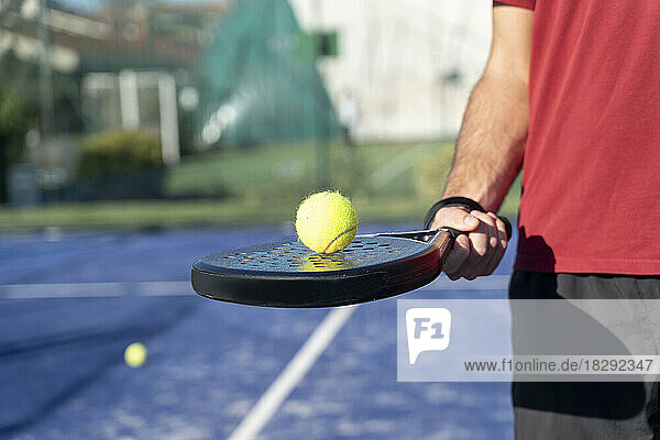 Hand eines Mannes mit Tennisschläger und Ball auf dem Sportplatz