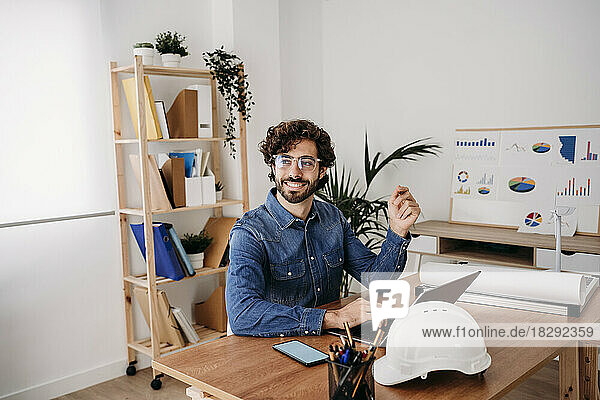 Nachdenklicher junger Ingenieur mit Laptop auf dem Schreibtisch im Büro