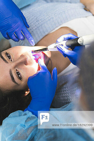 Dentist examining patient with equipment in medical clinic