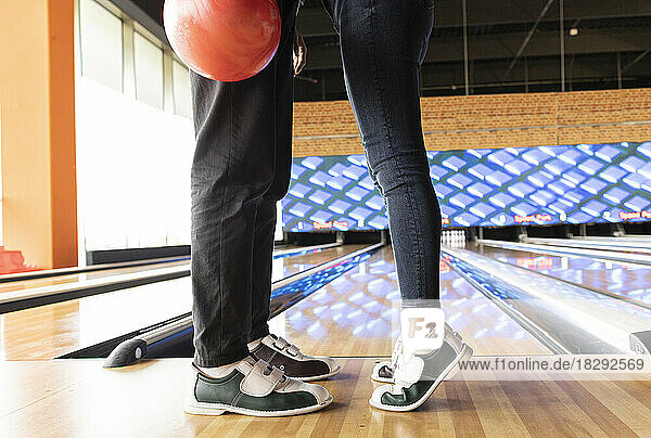 Woman standing on tiptoe with friend at bowling alley