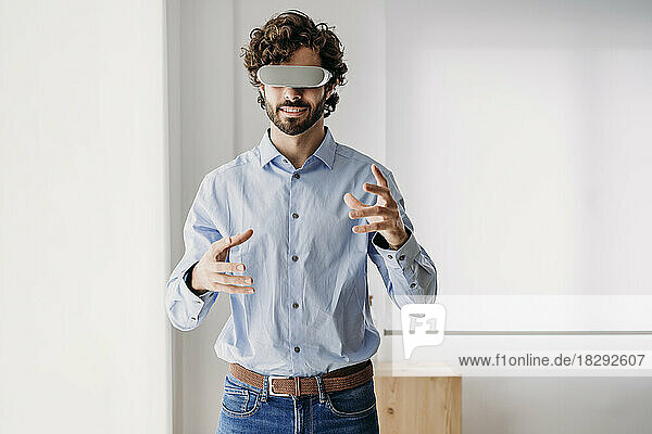Businessman wearing virtual reality glasses gesturing in office
