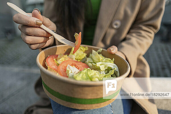 Young woman having bowl of salad