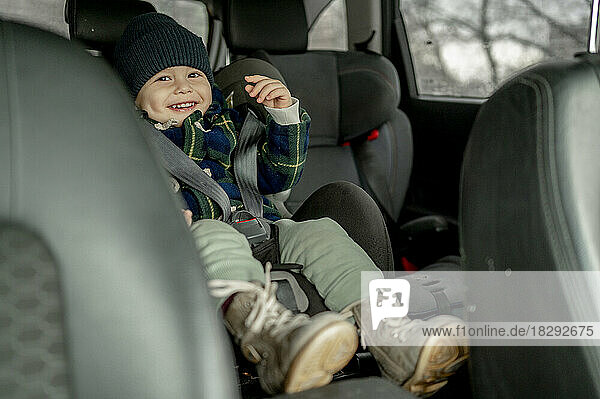 Fröhlicher süßer Junge im Autositz