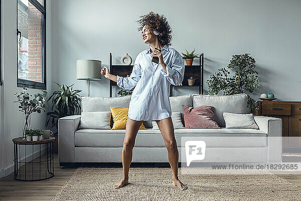 Playful young woman dancing in living room
