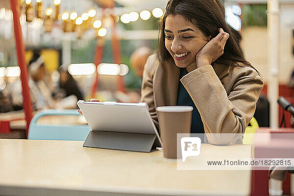 Glückliche junge Frau benutzt Tablet-Computer im Café