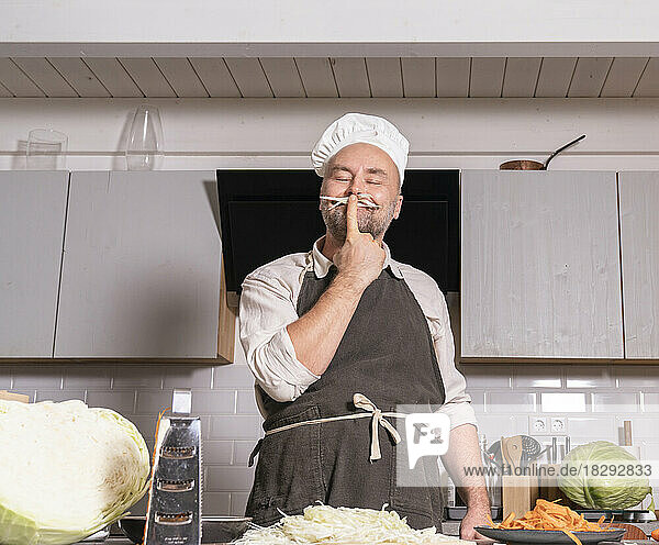 Playful man wearing chef clothing in kitchen at home