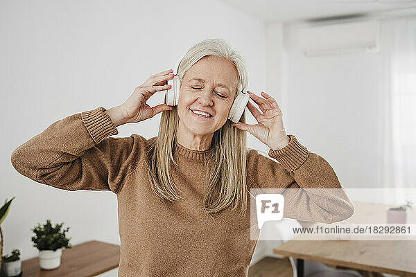 Happy woman with wireless headphones listening to music at home