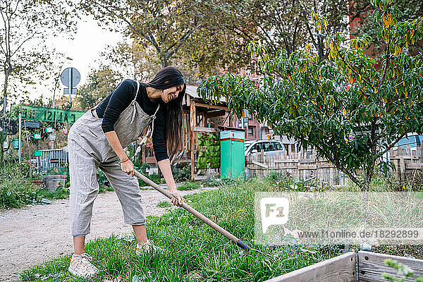 Happy woman gardening with shovel in urban garden