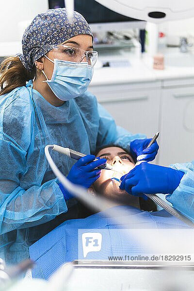 Dentist wearing protective eyewear examining patient in clinic
