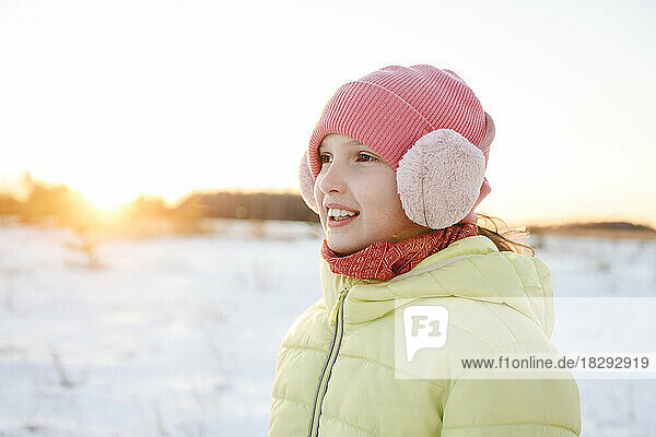 Fröhliches Mädchen mit Strickmütze und Ohrenschützer im Winterwald