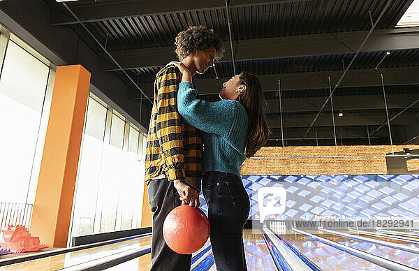 Young couple with bowling ball standing together at alley