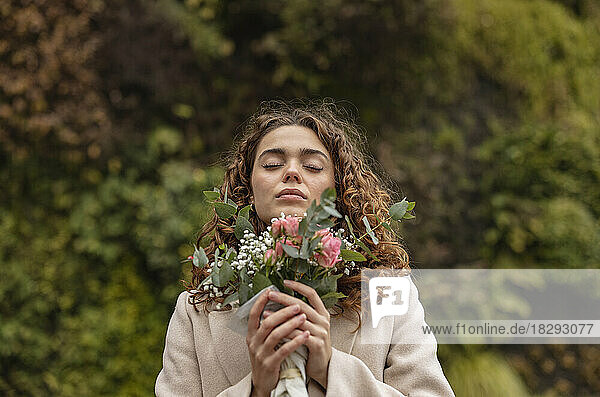 Young woman with eyes closed holding bouquet of flowers
