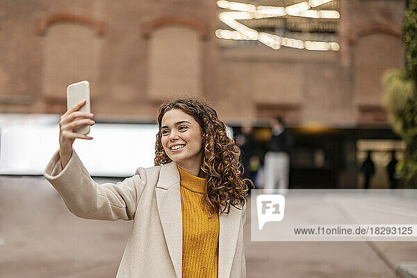 Happy young woman taking selfie through mobile phone