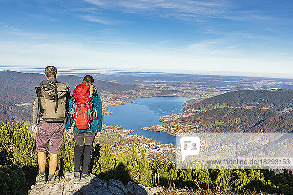 Germany  Bavaria  Rottach-Egern  Hiking couple admiring view of Lake Tegernsee and surrounding towns from summit of Wallberg mountain