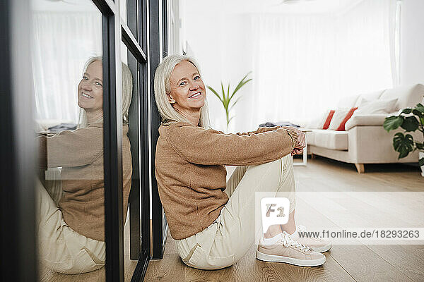 Happy woman sitting on floor in living room