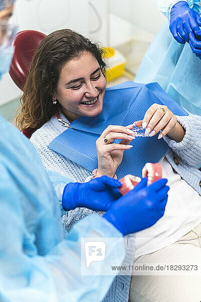 Dentist showing dental aligner to happy patient in clinic