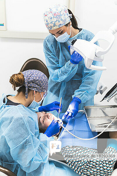 Dentist and assistant with equipment examining patient at clinic