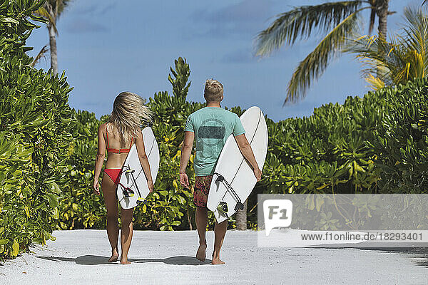 Couple with surfboards walking to the beach