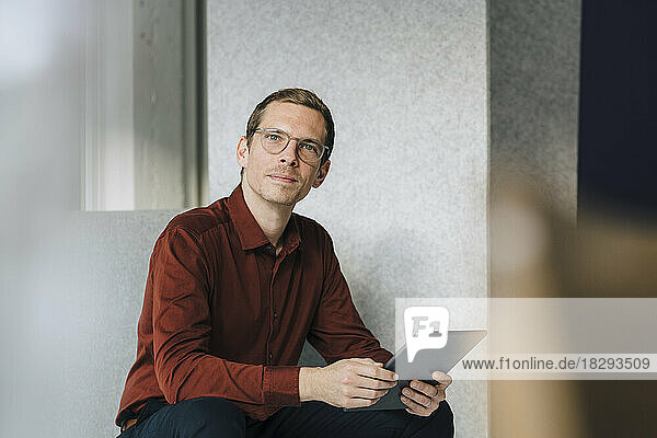 Businessman wearing eyeglasses holding tablet PC at office