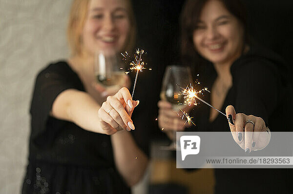 Happy friends celebrating Christmas with champagne glasses and sparklers
