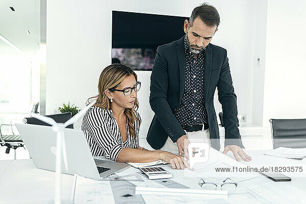 Architect explaining coworker over blueprint in office