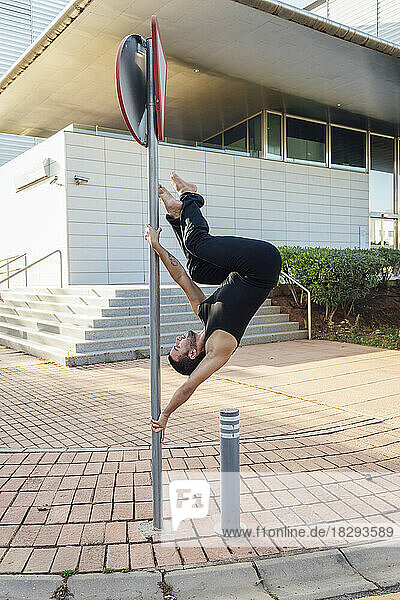 Man practicing pole dance outside building