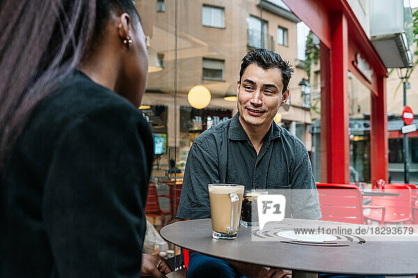 Smiling businessman discussing with colleague at sidewalk cafe