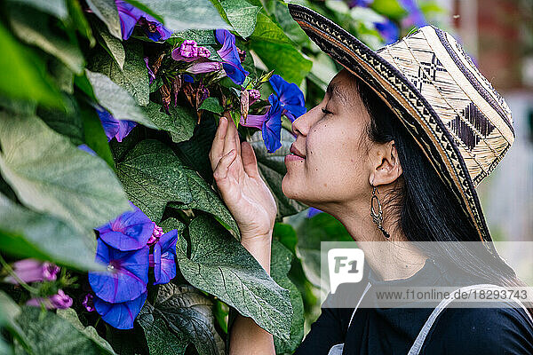 Lächelnde Frau riecht Blumen im Garten
