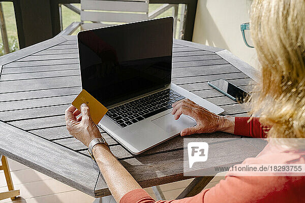 Woman with credit card doing online shopping through laptop at table