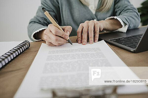 Freelancer signing documents with pen at desk