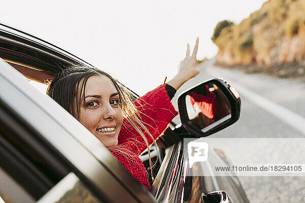 Frau im Auto blickt in die Kamera  die auf die Straße zeigt