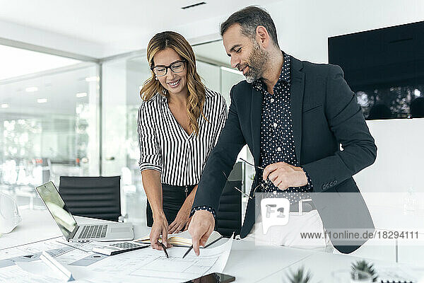 Happy businesswoman and colleague discussing plans in office