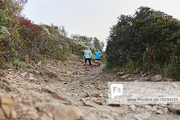 Couple running down on rocky path in morning