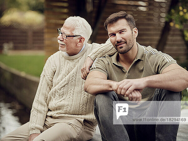 Erwachsener Sohn sitzt mit Vater im Garten