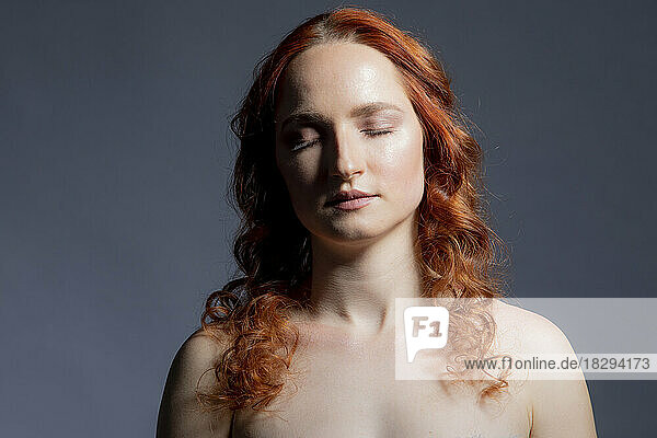 Young redhead woman against gray background