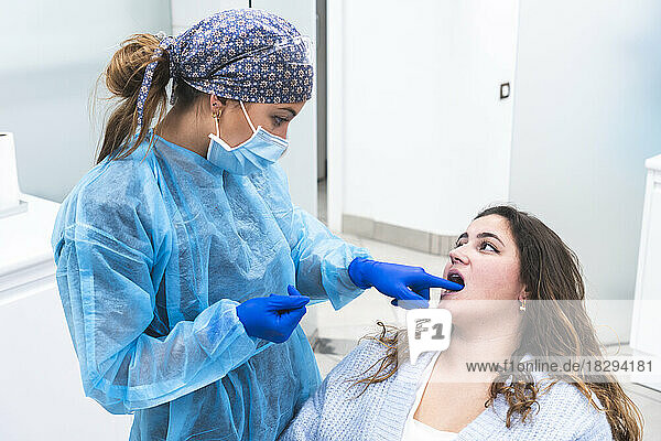 Dentist examining teeth of woman at clinic